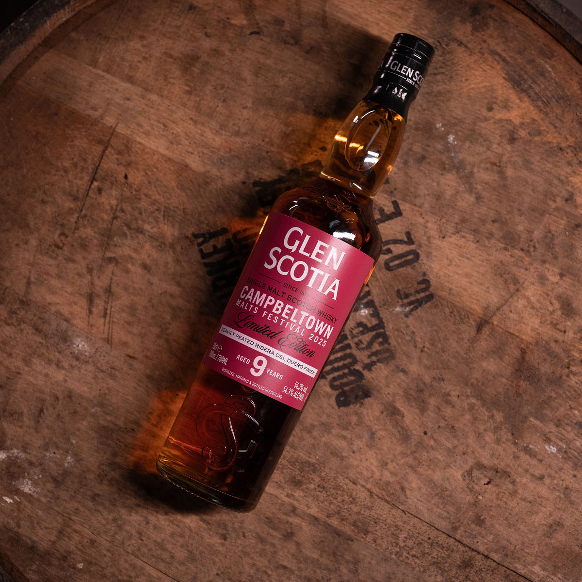 A bottle of Glen Scotia Campbeltown Malts Festival Edition 2025 sits on a wooden barrel, featuring a deep red label that emphasizes 9 years of aging in Ribera del Duero red wine casks and an alcohol content of 56.8%.